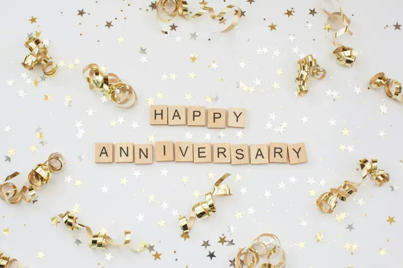 Happy Anniversary celebration with golden decorations and festive confetti